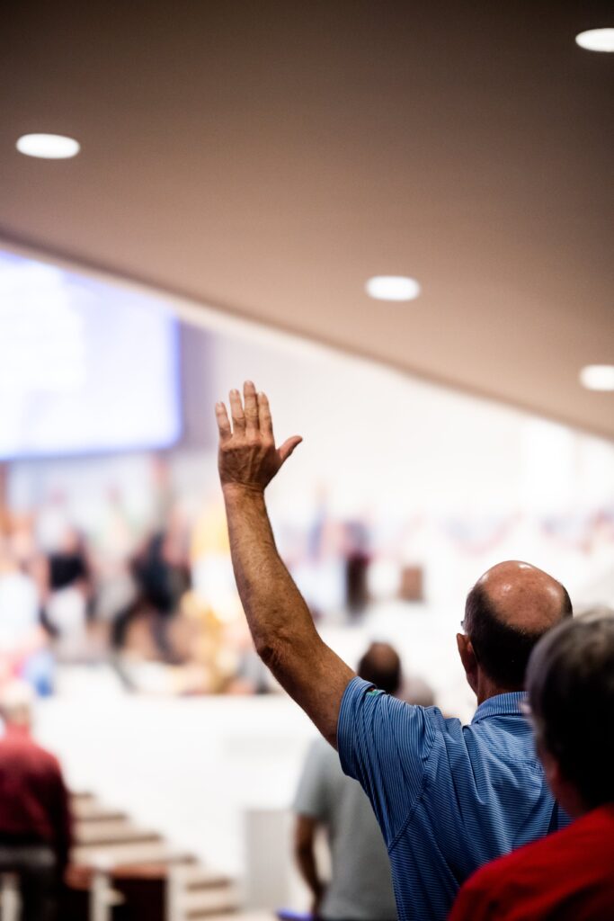 A photo of a person raising their hand to ask a question taken.