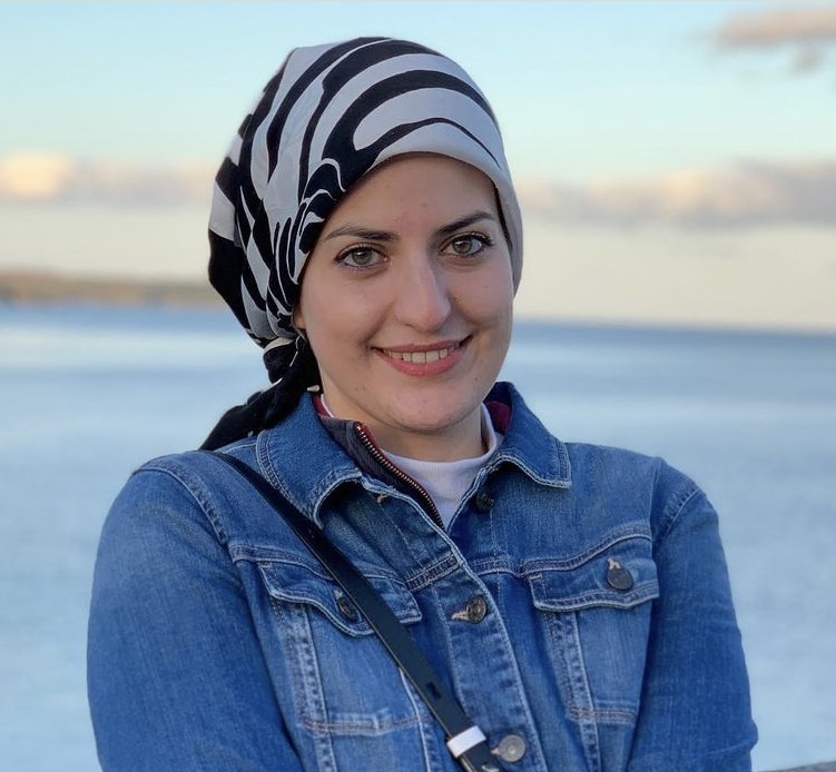 A picture of Sana Sharrack from the shoulders up with a hilly landscape behind them.