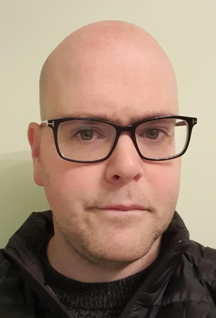 A headshot picture of Matt Clark from the neck up against a pale background.