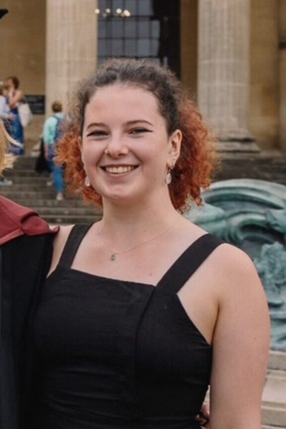 An image of Zoe Brown in front of a building with stone columns.