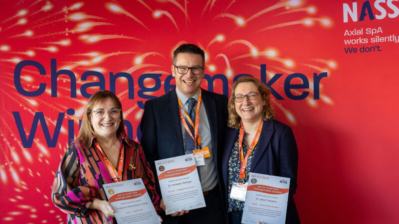 An image of the three winners standing against a red background with their awards.