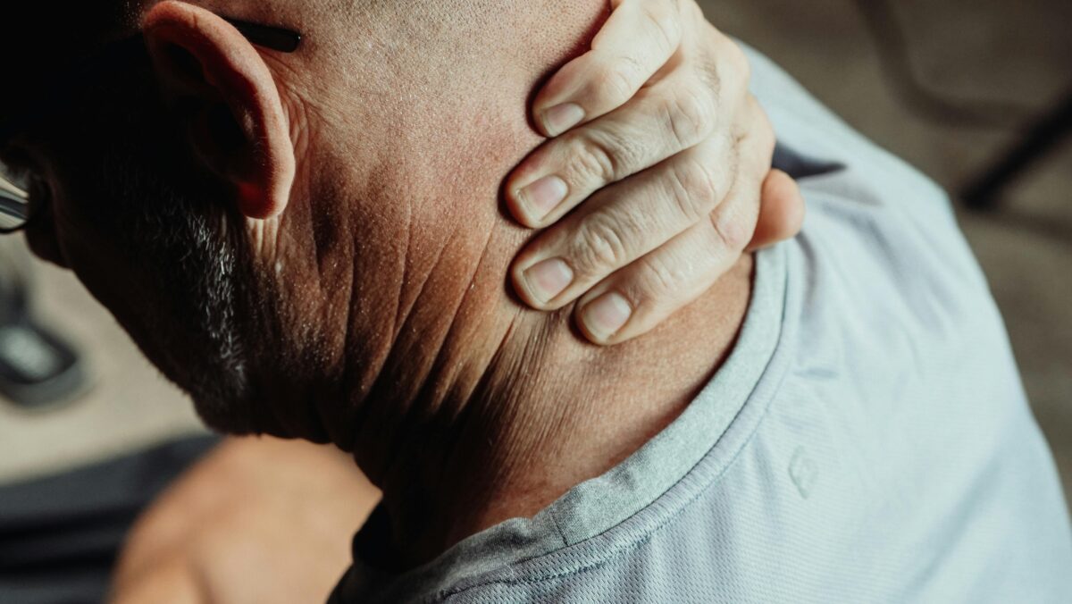 An image of an older male patient holding their neck, representing neck and shoulder pain, one of the key symptoms of polymyalgia rheumatica (PMR)